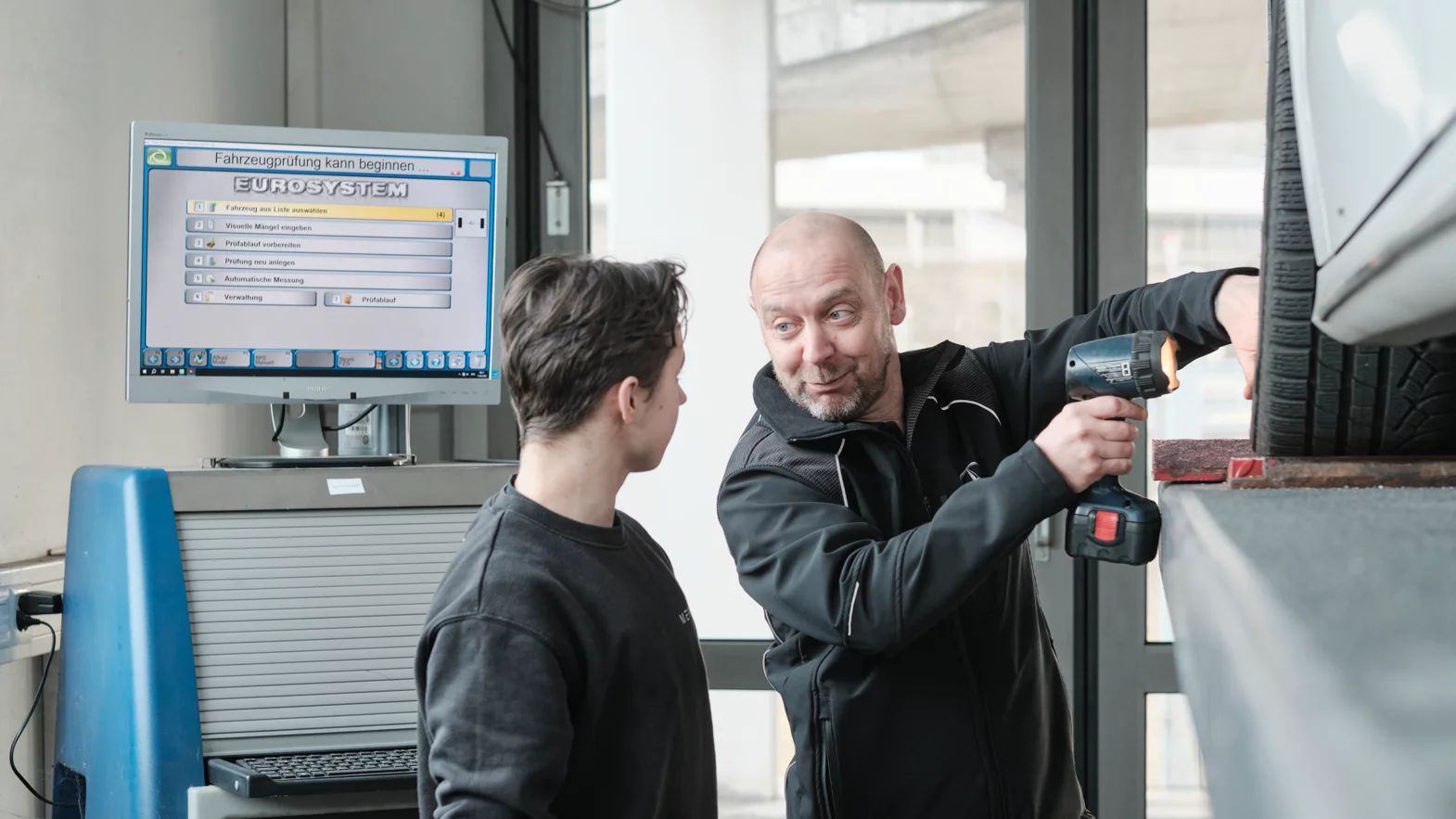 Meccatronico/a d’automobili AFC specializzazione veicoli utilitari con il formatore professionale durante il lavoro.