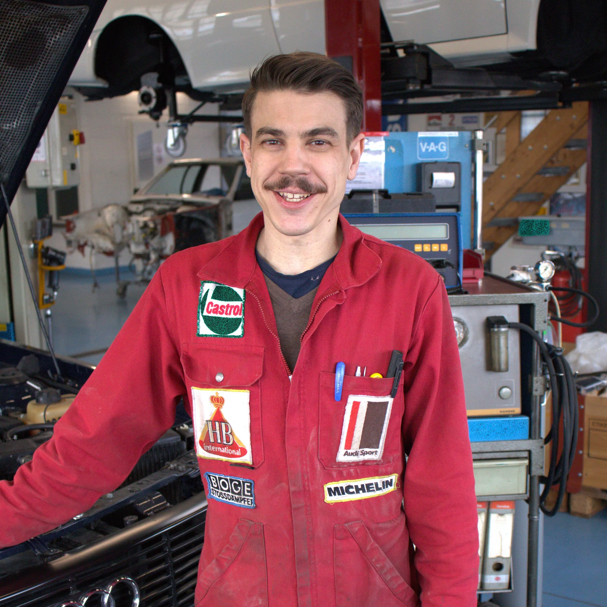 Fahrzeugrestaurator:in mit eidg. Fachausweis in Arbeitskleidung.
